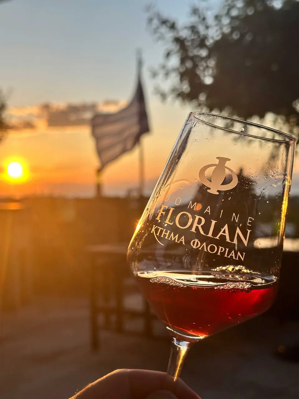 A glass etched with “Domaine Florian” held up against the sunset